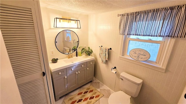 bathroom with a textured ceiling, tile walls, vanity, and toilet