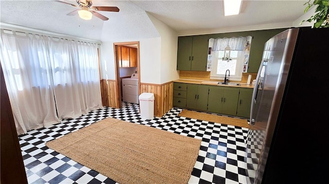 kitchen with stainless steel refrigerator, ceiling fan, green cabinets, washer / dryer, and a textured ceiling