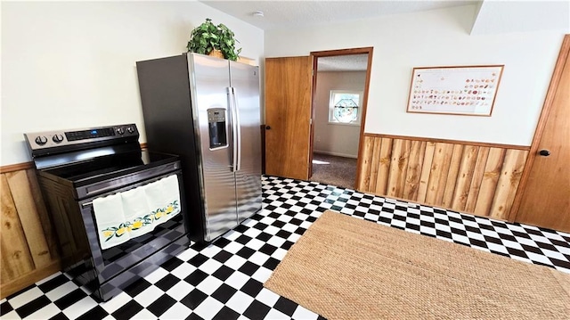 kitchen with stainless steel fridge, range with electric stovetop, and wooden walls