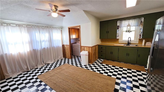 kitchen featuring washer / clothes dryer, green cabinets, sink, and ceiling fan