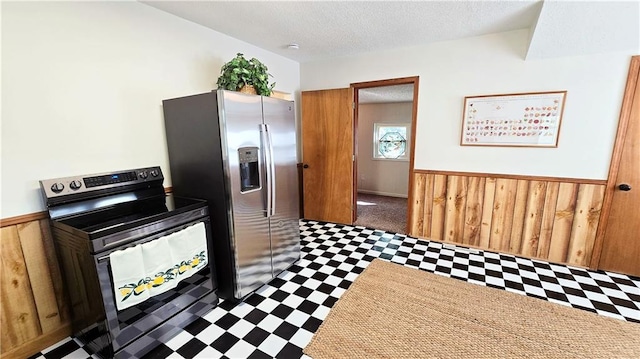 kitchen featuring stainless steel appliances, dark carpet, wooden walls, and a textured ceiling