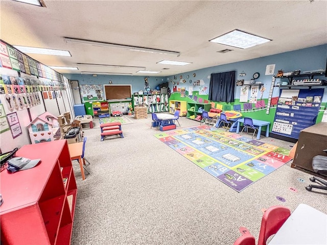 playroom with carpet floors and a textured ceiling