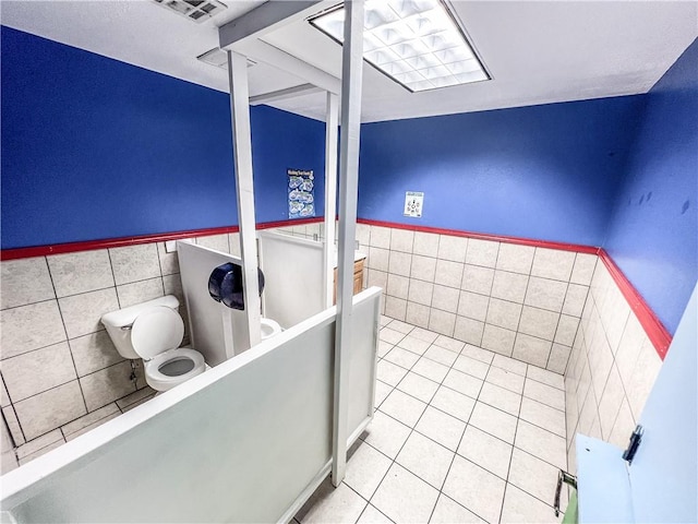 bathroom featuring tile walls, tile patterned flooring, and toilet