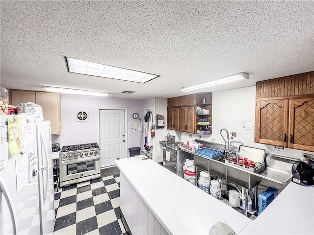 1201 S Willow St, Coffeyville, KS 67337 - kitchen featuring freestanding refrigerator, stainless steel range, tile patterned floors, open shelves, and a textured ceiling