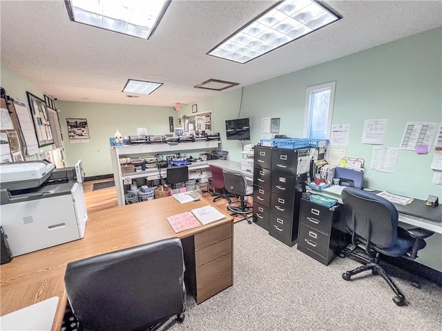 home office with a textured ceiling and light hardwood / wood-style flooring