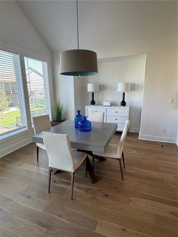 dining room with hardwood / wood-style flooring and high vaulted ceiling