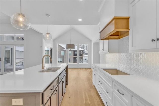 kitchen featuring white cabinetry, light countertops, light wood-type flooring, and a sink