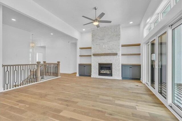 unfurnished living room with a ceiling fan, baseboards, recessed lighting, a stone fireplace, and light wood-type flooring