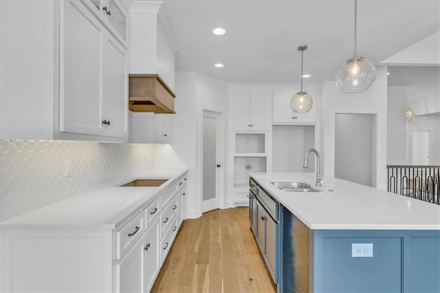 kitchen with a sink, light wood-style floors, white cabinetry, black electric cooktop, and backsplash