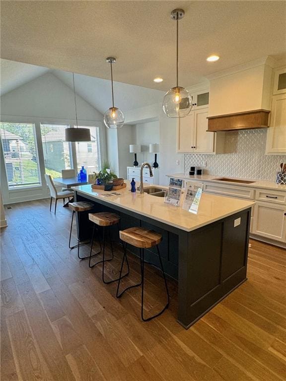 kitchen with a kitchen island with sink, white cabinetry, light countertops, decorative backsplash, and black electric stovetop