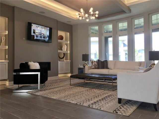 16928 Futura St, Overland Park, KS 66085 - living room featuring a raised ceiling, a chandelier, wood tiled floors, built in features, and baseboards