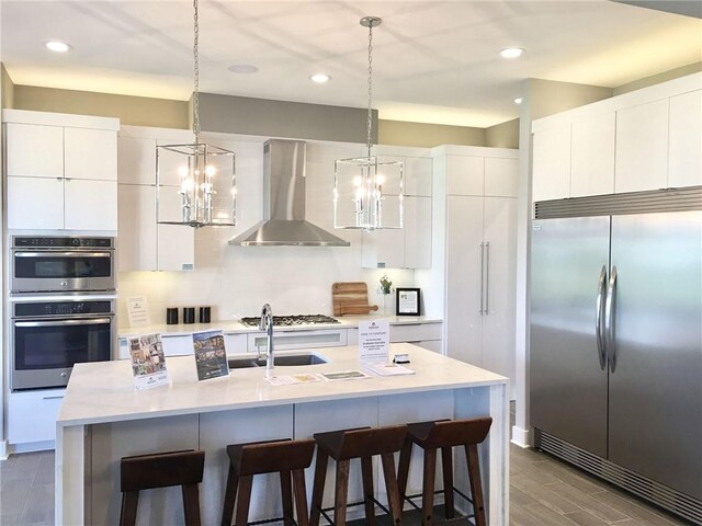 16928 Futura St, Overland Park, KS 66085 - kitchen featuring appliances with stainless steel finishes, wall chimney exhaust hood, a chandelier, modern cabinets, and recessed lighting