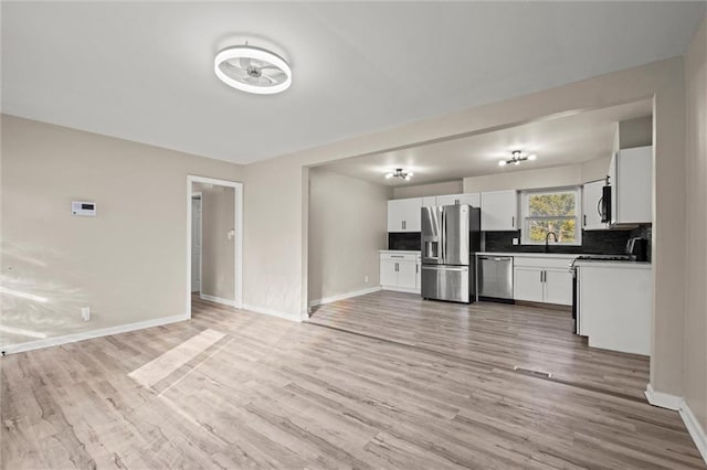 kitchen with sink, appliances with stainless steel finishes, light hardwood / wood-style flooring, and white cabinetry