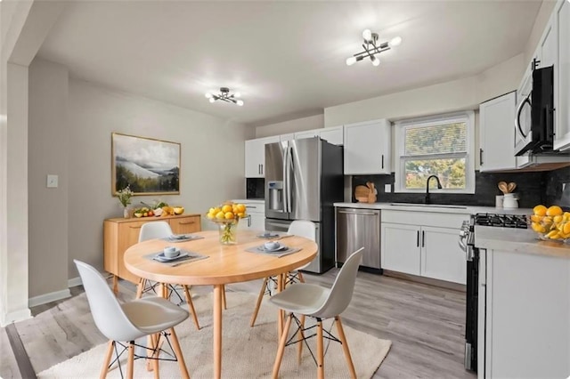 kitchen with light hardwood / wood-style flooring, white cabinetry, stainless steel appliances, and sink