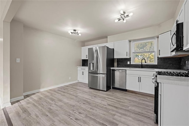 kitchen with sink, white cabinets, light hardwood / wood-style flooring, and stainless steel appliances