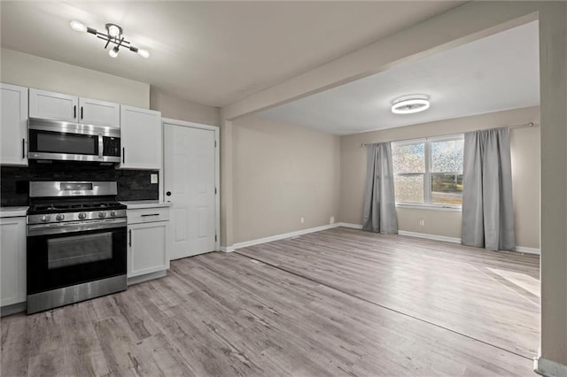 kitchen with white cabinetry, stainless steel appliances, decorative backsplash, and light wood-type flooring