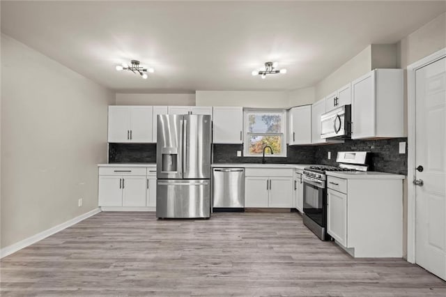 kitchen with stainless steel appliances, backsplash, sink, light wood-type flooring, and white cabinets