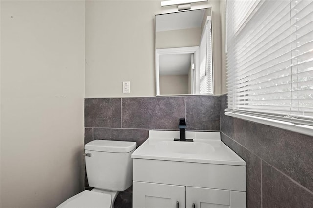 bathroom with vanity, toilet, and tile walls