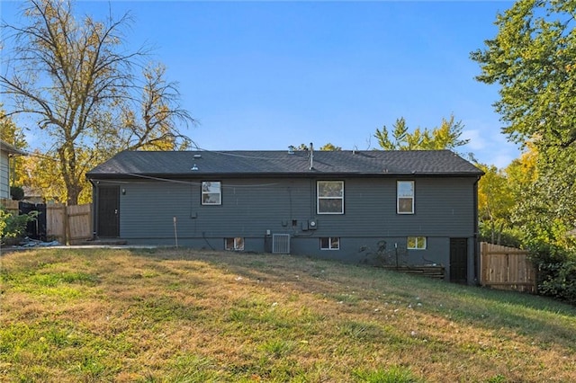 rear view of house with central air condition unit and a lawn