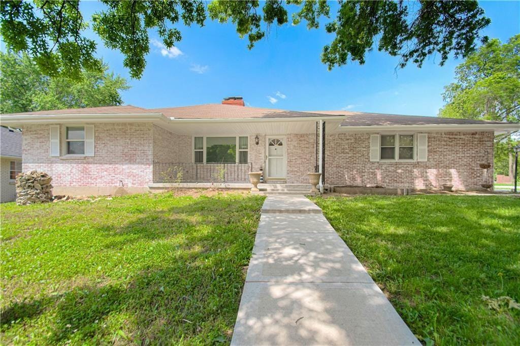 ranch-style home featuring covered porch and a front lawn