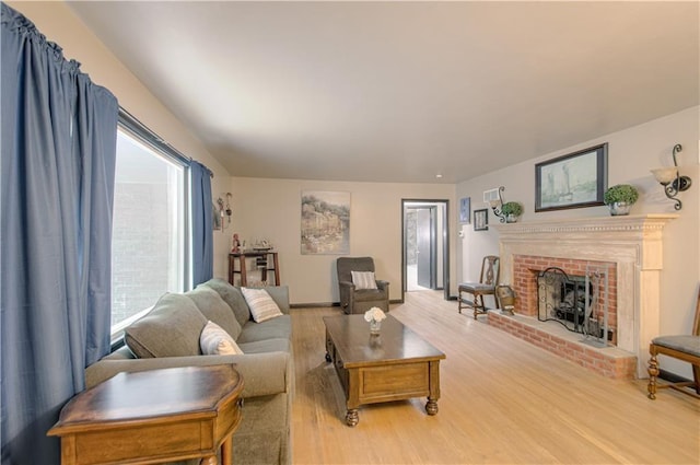 living room featuring a brick fireplace and light wood-type flooring