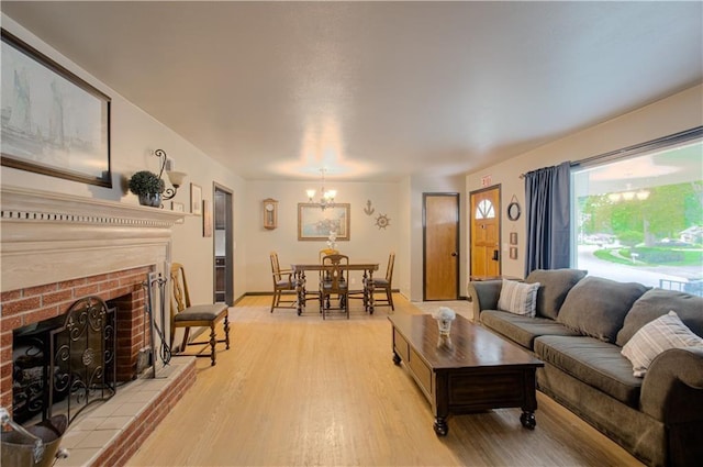 living room with a notable chandelier, light hardwood / wood-style floors, and a fireplace