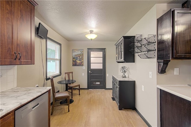 kitchen featuring light hardwood / wood-style flooring, stainless steel dishwasher, a textured ceiling, decorative backsplash, and dark brown cabinets