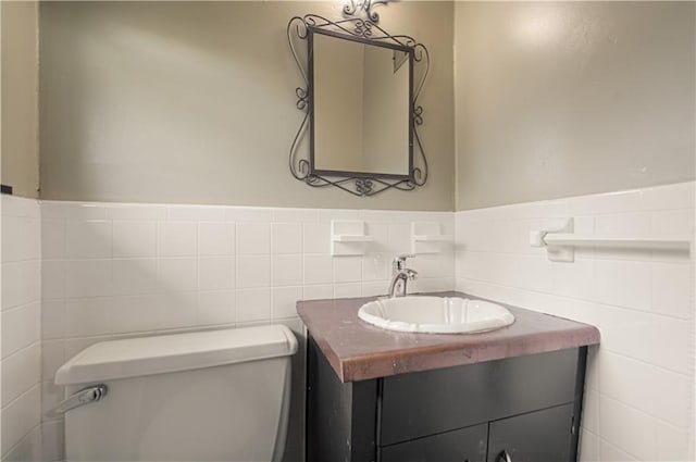 bathroom with vanity, tile walls, and toilet