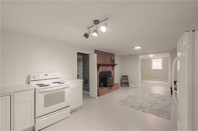 kitchen with white cabinetry, white appliances, and a wood stove