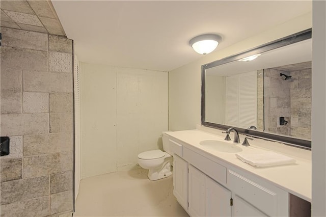 bathroom with vanity, toilet, concrete flooring, and tiled shower