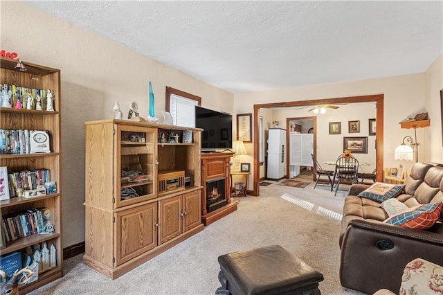 living room with a textured ceiling, light colored carpet, and ceiling fan