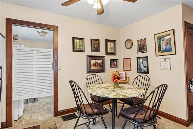 dining area with ceiling fan and light colored carpet