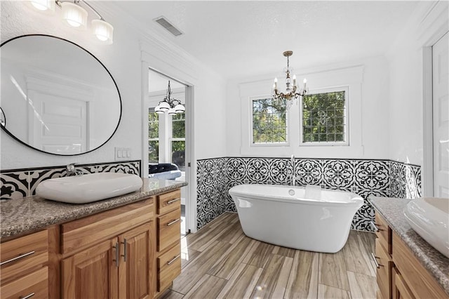 bathroom with a bathing tub, tile walls, vanity, and a chandelier