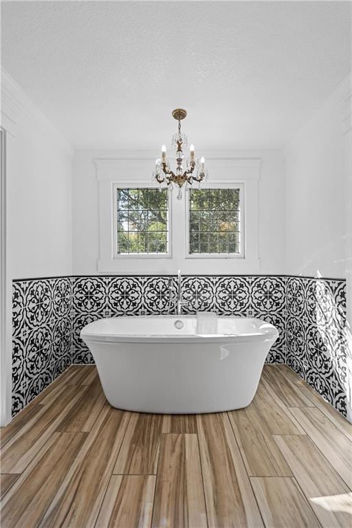 bathroom with a bathtub, plenty of natural light, wood-type flooring, and a chandelier