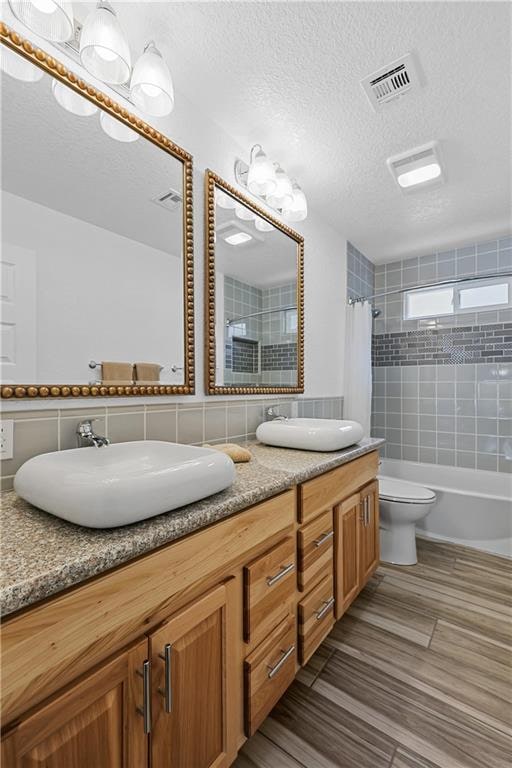 bathroom featuring a textured ceiling, a shower with shower curtain, vanity, and toilet