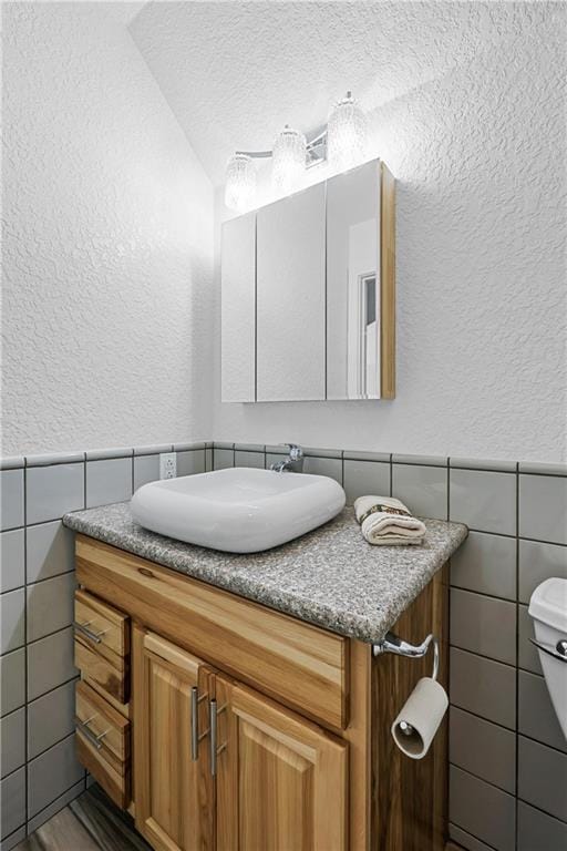 bathroom with vanity, tile walls, and toilet