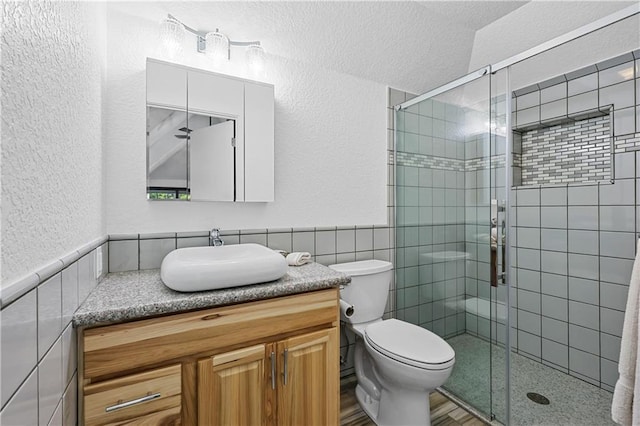 bathroom featuring vanity, tile walls, toilet, and an enclosed shower