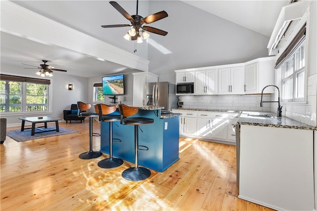 kitchen featuring black microwave, stainless steel fridge with ice dispenser, white cabinetry, dark stone counters, and light hardwood / wood-style floors