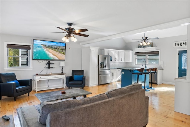 living room with sink, light hardwood / wood-style floors, vaulted ceiling, and ceiling fan