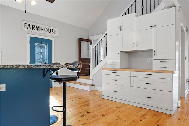 kitchen with white cabinetry, vaulted ceiling, and light hardwood / wood-style flooring