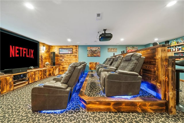 home theater room featuring wooden walls and dark colored carpet