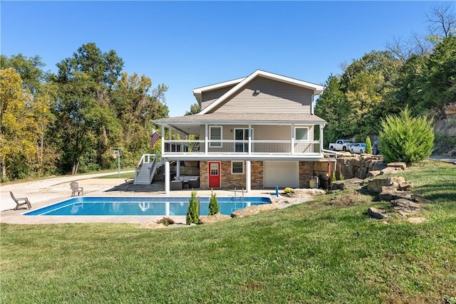 back of house with a lawn, stone siding, a patio, an outdoor pool, and stairs