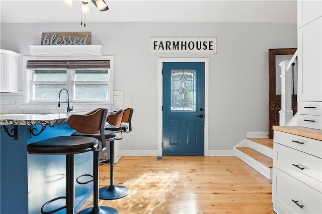 entryway featuring light wood finished floors, stairs, and baseboards