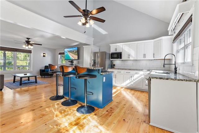 kitchen with dark stone countertops, a sink, stainless steel refrigerator with ice dispenser, black microwave, and open floor plan