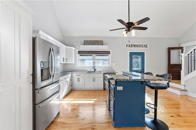 kitchen with a sink, a kitchen breakfast bar, white cabinets, and stainless steel fridge with ice dispenser