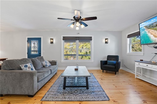 living area featuring a ceiling fan, light wood-style floors, and baseboards