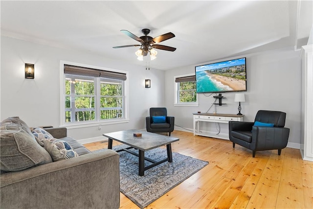 living area featuring light wood-type flooring, baseboards, and ceiling fan