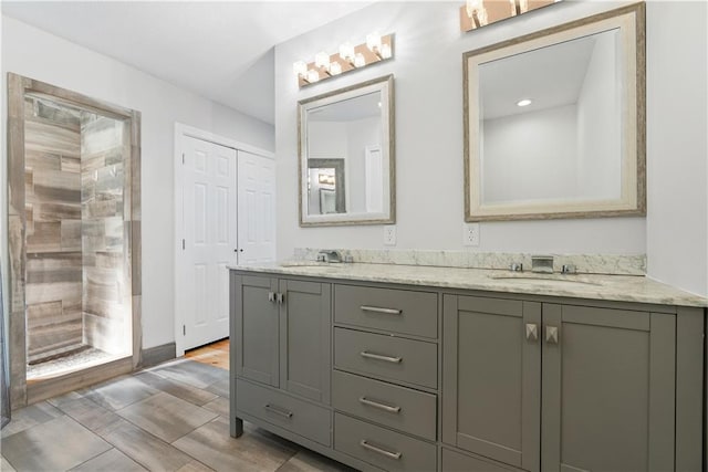 bathroom with double vanity, a tile shower, and a sink