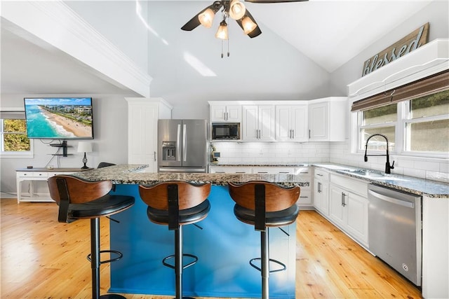 kitchen with tasteful backsplash, light stone countertops, white cabinets, stainless steel appliances, and a sink