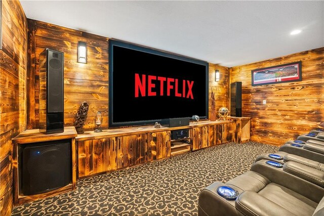 living area featuring carpet, wood walls, and a wood stove